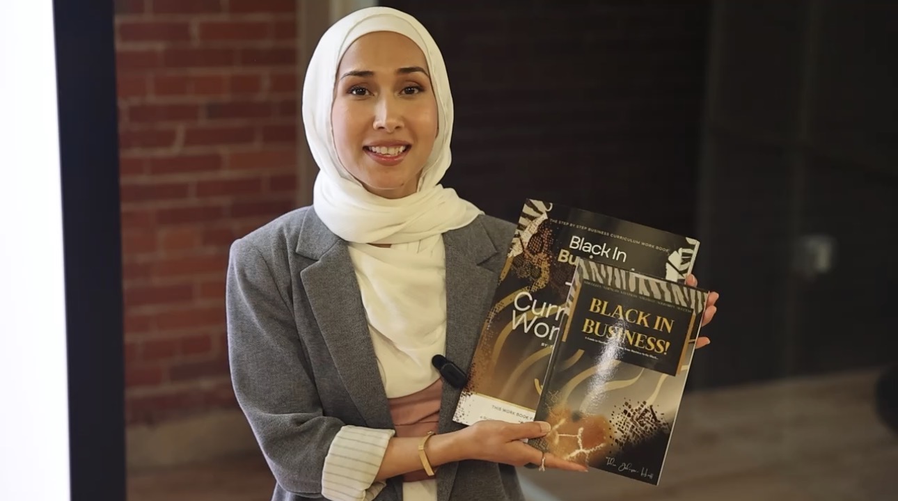 A business owner holding the Black in Business book and the Curriculum workbook