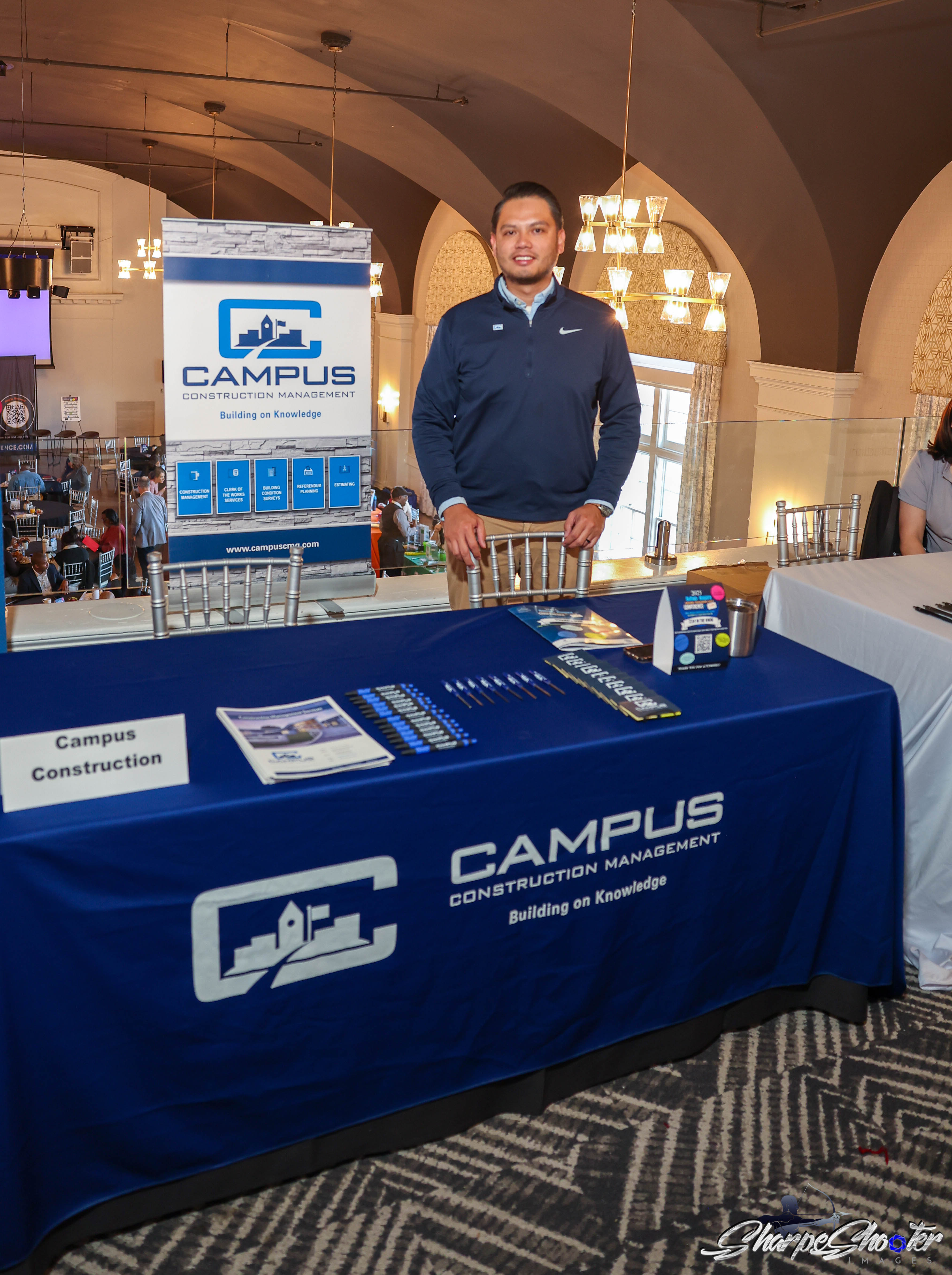 Campus Construction Management at their exhibitor table with branded banner and materials